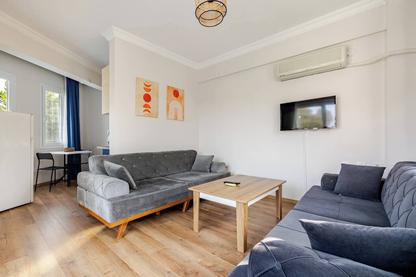 Un salón moderno con un sofá gris, una mesa de centro de madera y un televisor montado en la pared.