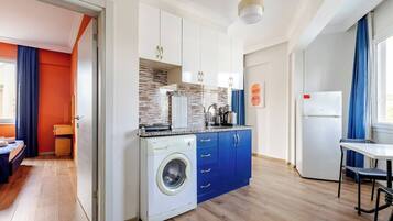 A compact kitchen with a washing machine, a microwave, and a refrigerator.