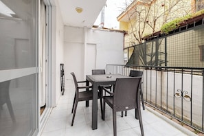 A patio with a table and chairs, a sliding glass door, and a metal fence.