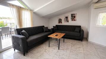 Una sala moderna con un sofá modular, una mesa de centro de madera y un comedor con sillas.