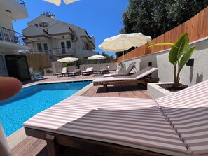 A pool area with lounge chairs and umbrellas.