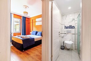 A hotel room with a bed, a bathroom with a toilet, and a shower. - Nehir Apart Otel (Fethiye)