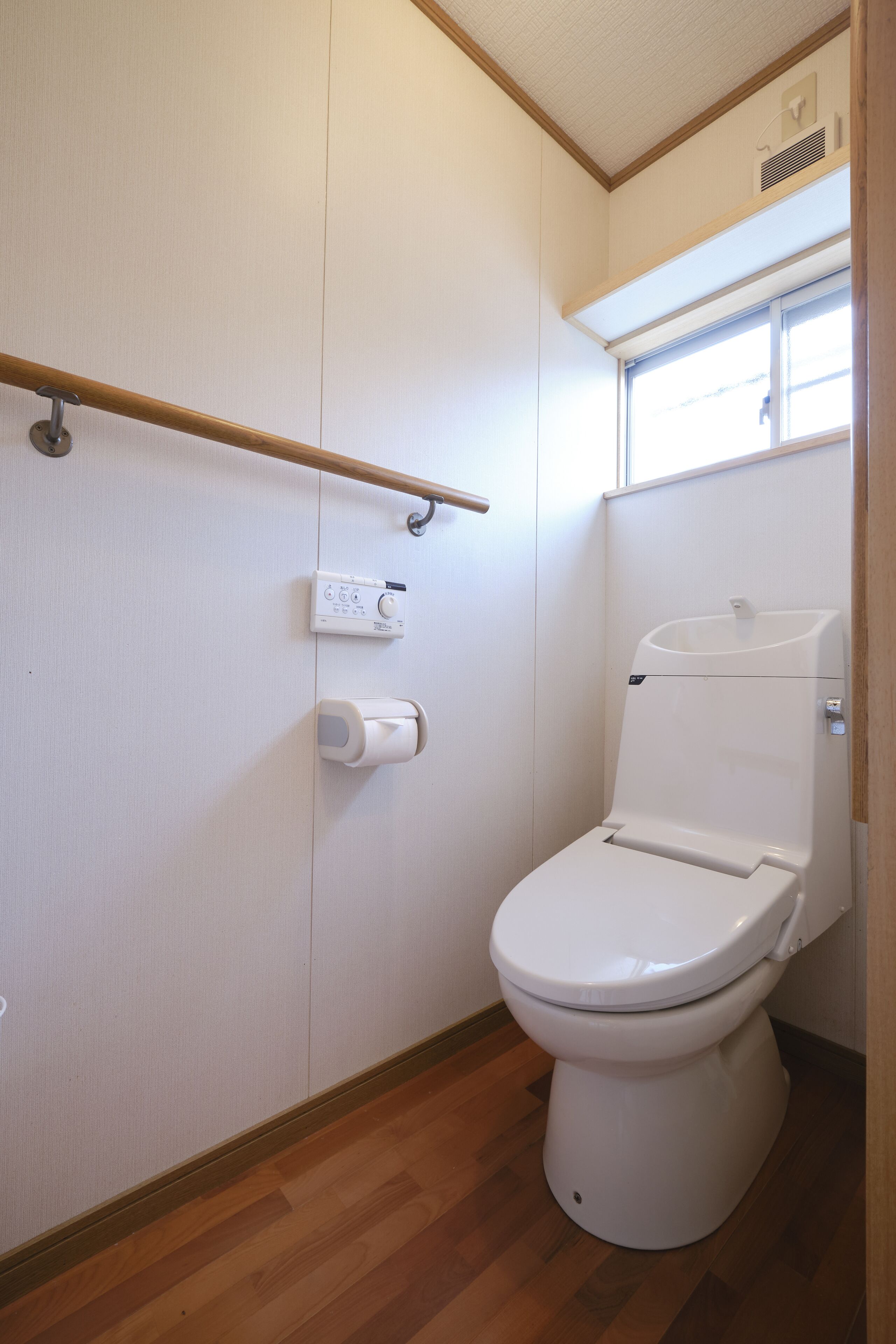 A compact bathroom with a toilet, a hand dryer, and a paper towel dispenser.