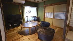 Een traditionele Japanse kamer met tatami vloeren, een lage tafel, een relax fauteuil, een televisie en een verschuifbare shoji-scherm.