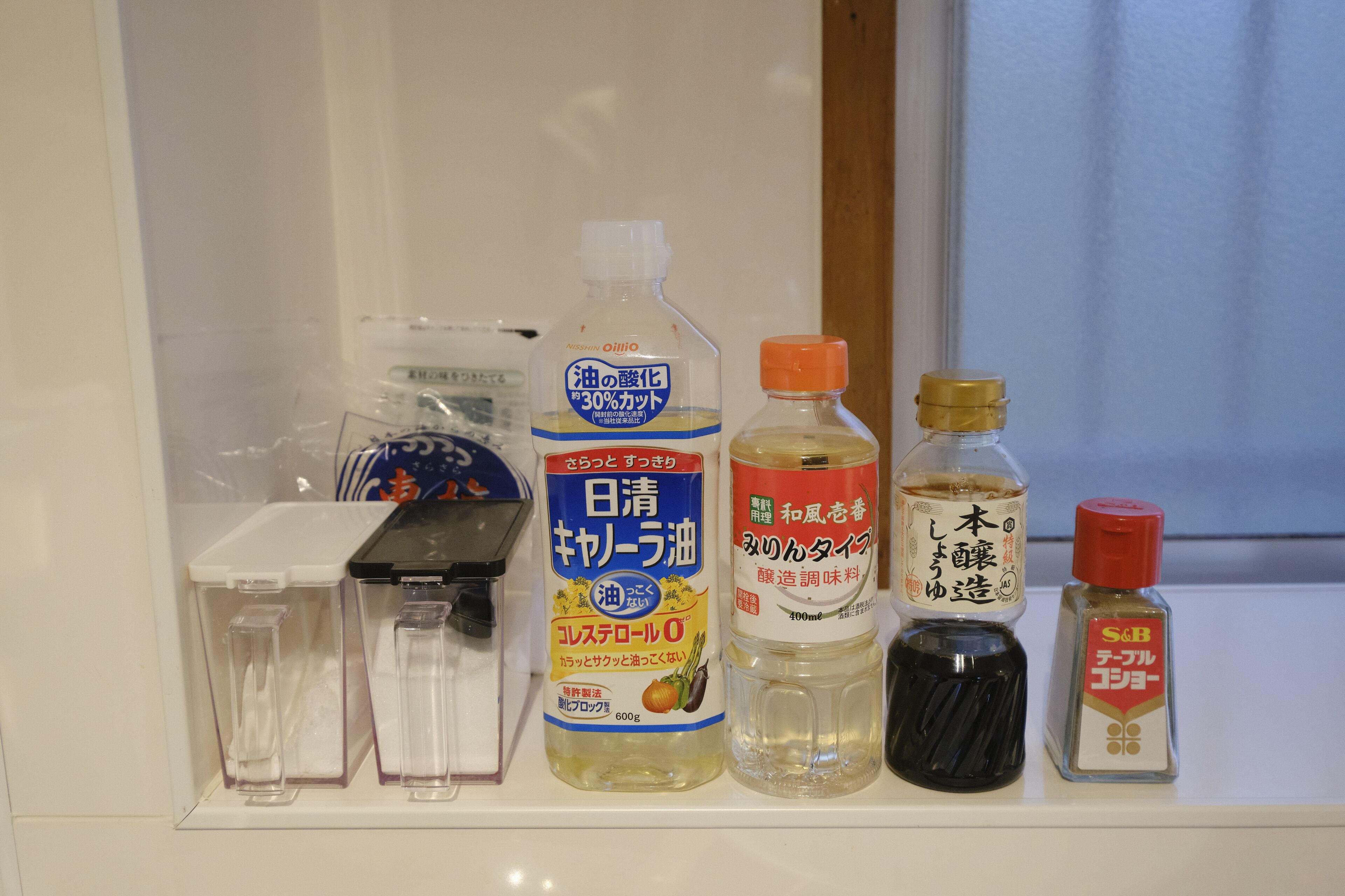 A shelf with various bottles and containers, including a bottle labeled with Japanese text and a small bottle with a red cap.