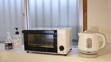 A kitchen with a microwave, a kettle, and two bottles of hand sanitizer on a counter.