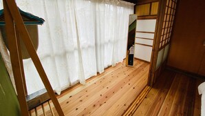 Een kamer met houten vloeren, een wit gordijn en een houten ladder.