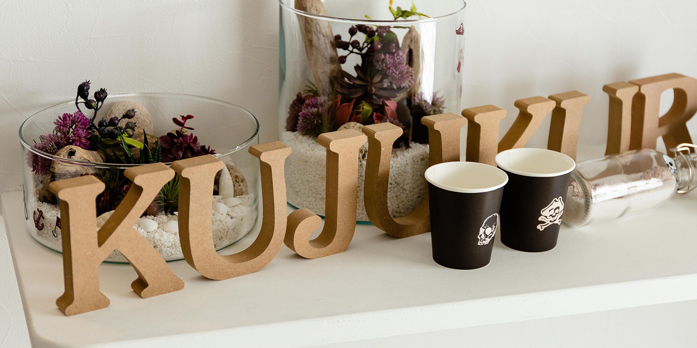 A decorative setup with letters spelling "KUJUR" and two black cups with skull designs.
