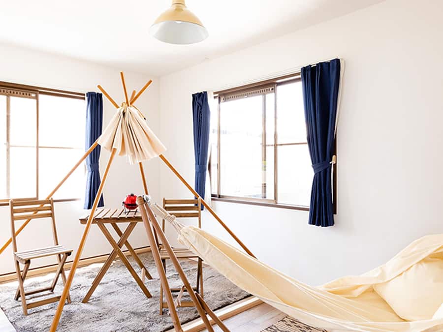 Una habitación con una hamaca, un caballete de madera y una mesita.
