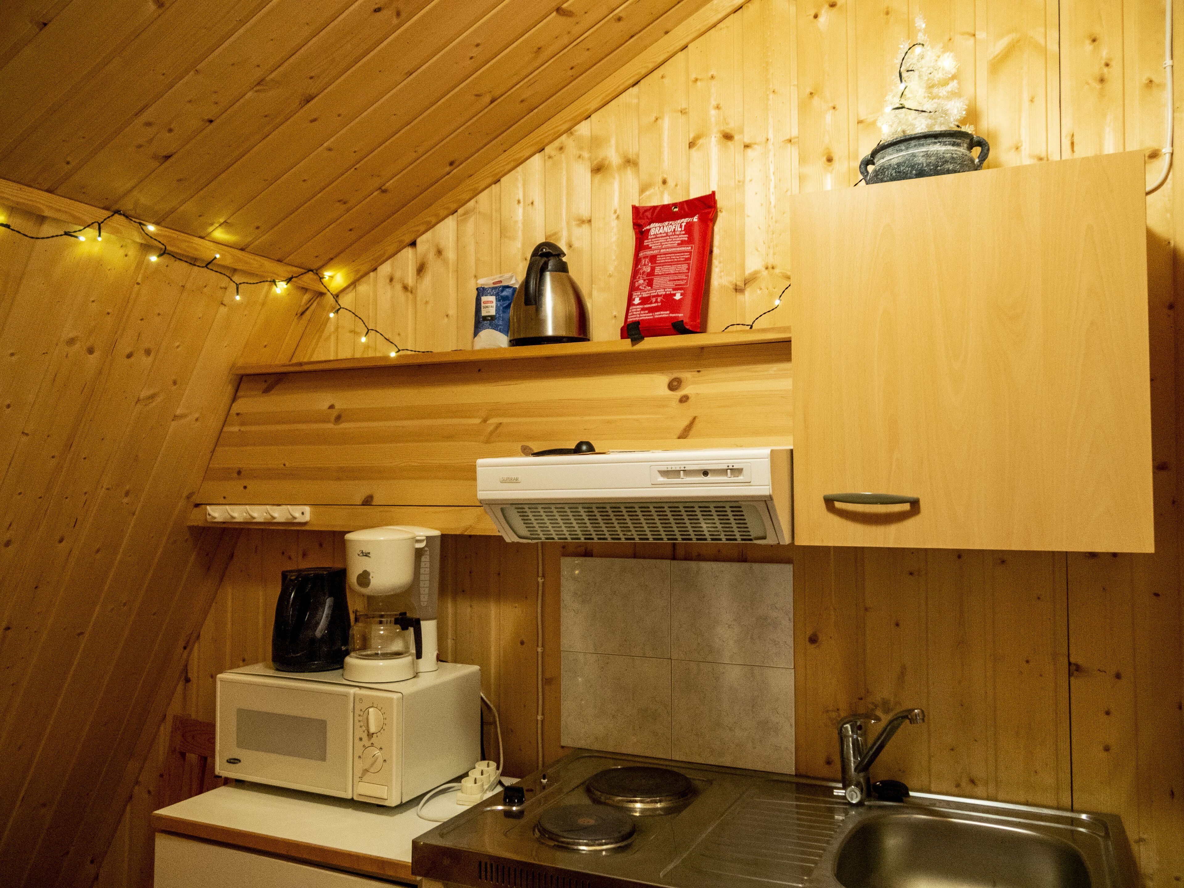 Una cocina compacta con microondas, cafetera y lavabo.