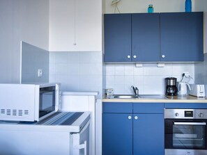 A kitchen with a microwave, coffee maker, toaster, and oven.
