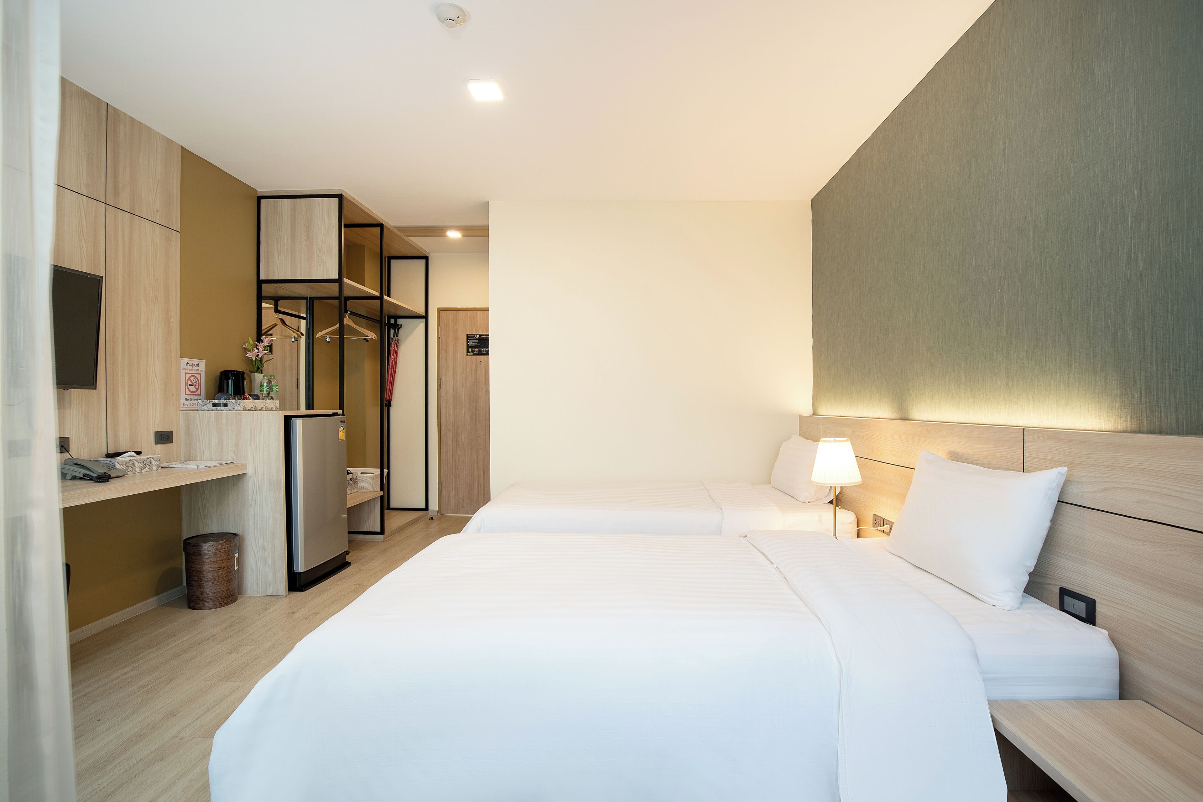 Una habitación de hotel con cama, mesita de noche, lámpara y armario.