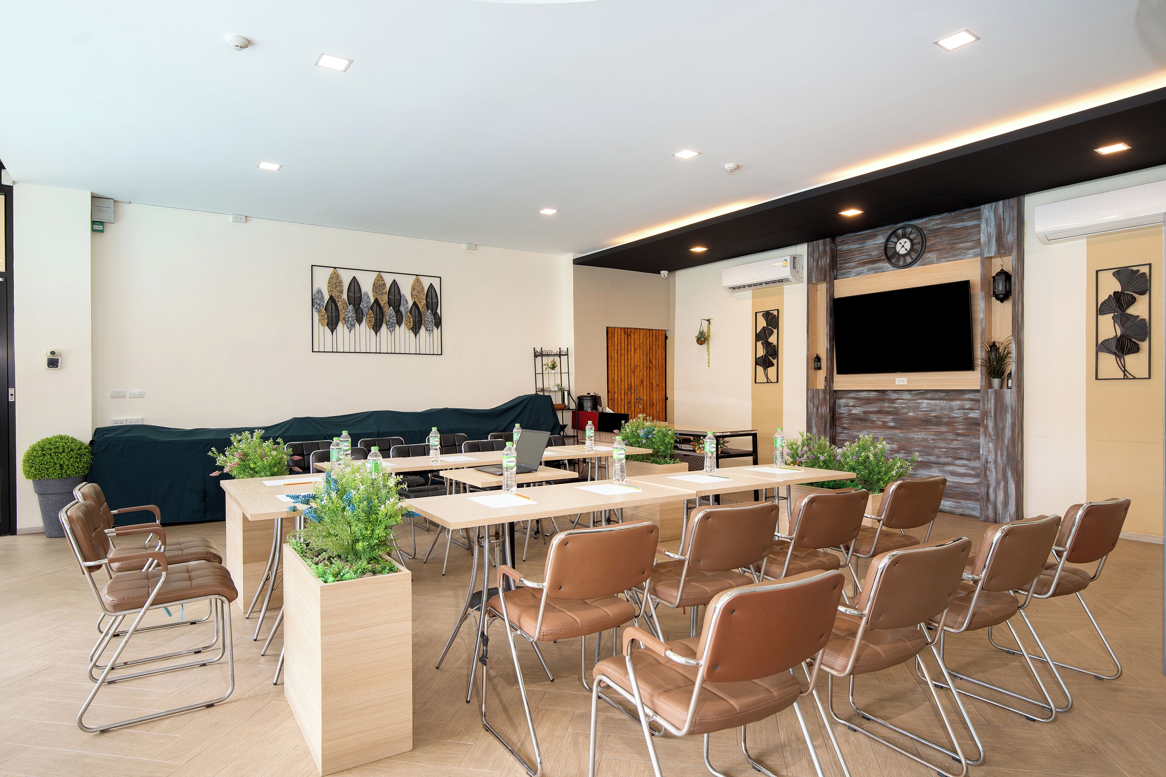 A conference room with tables, chairs, and a large screen.