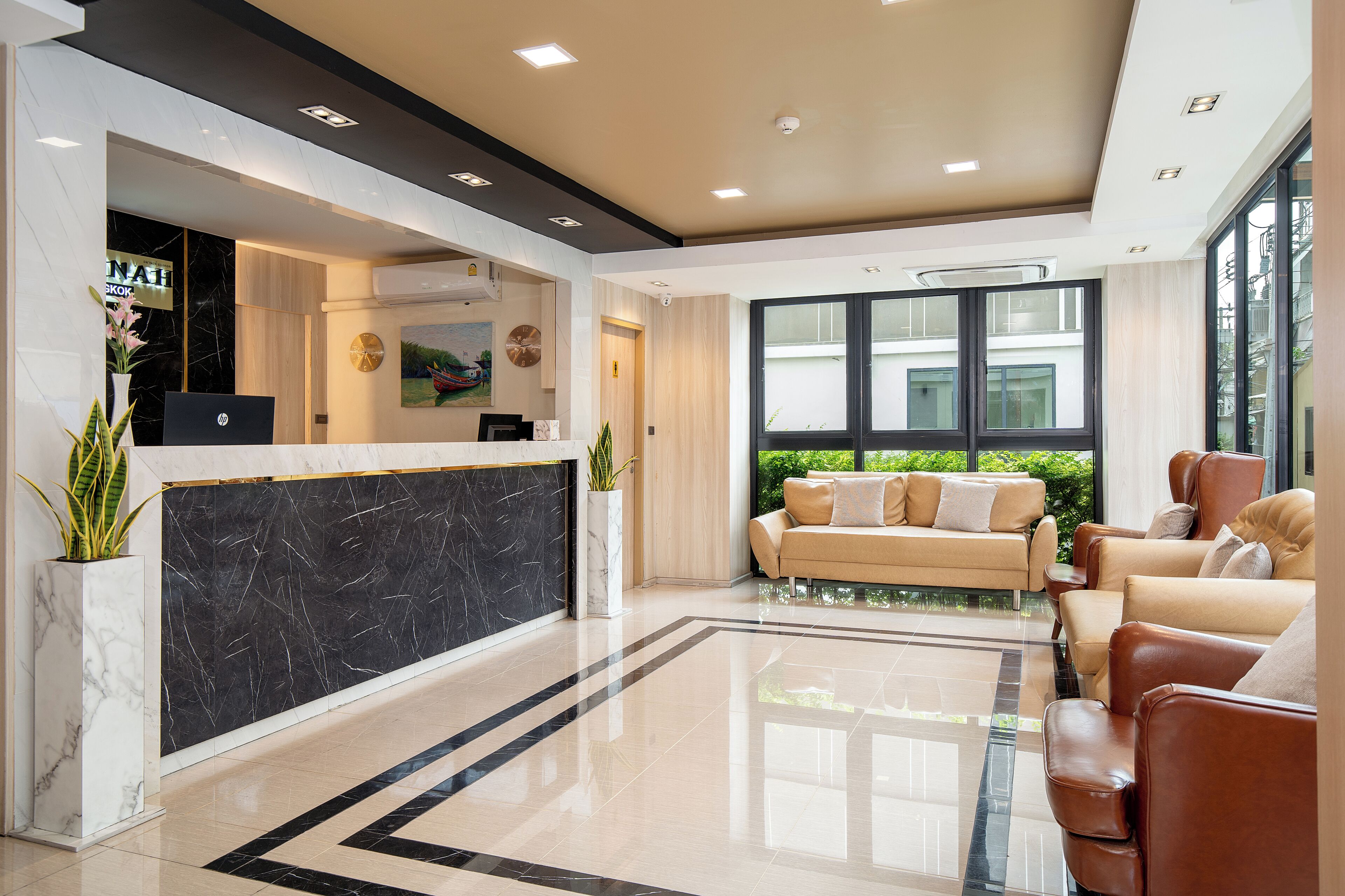 A modern reception area with a marble reception desk, leather seating, and large windows offering views of the outdoors.