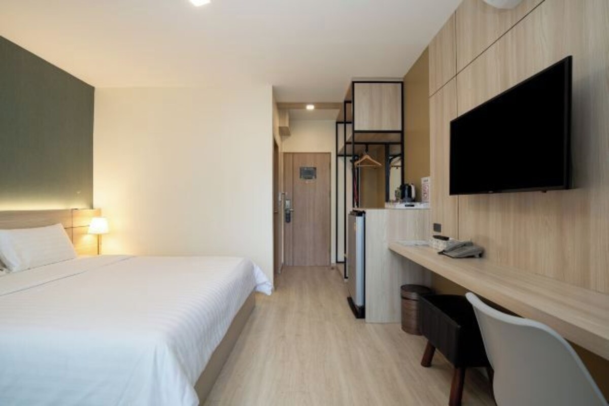 A hotel room with a bed, a desk, a TV, and a wardrobe.
