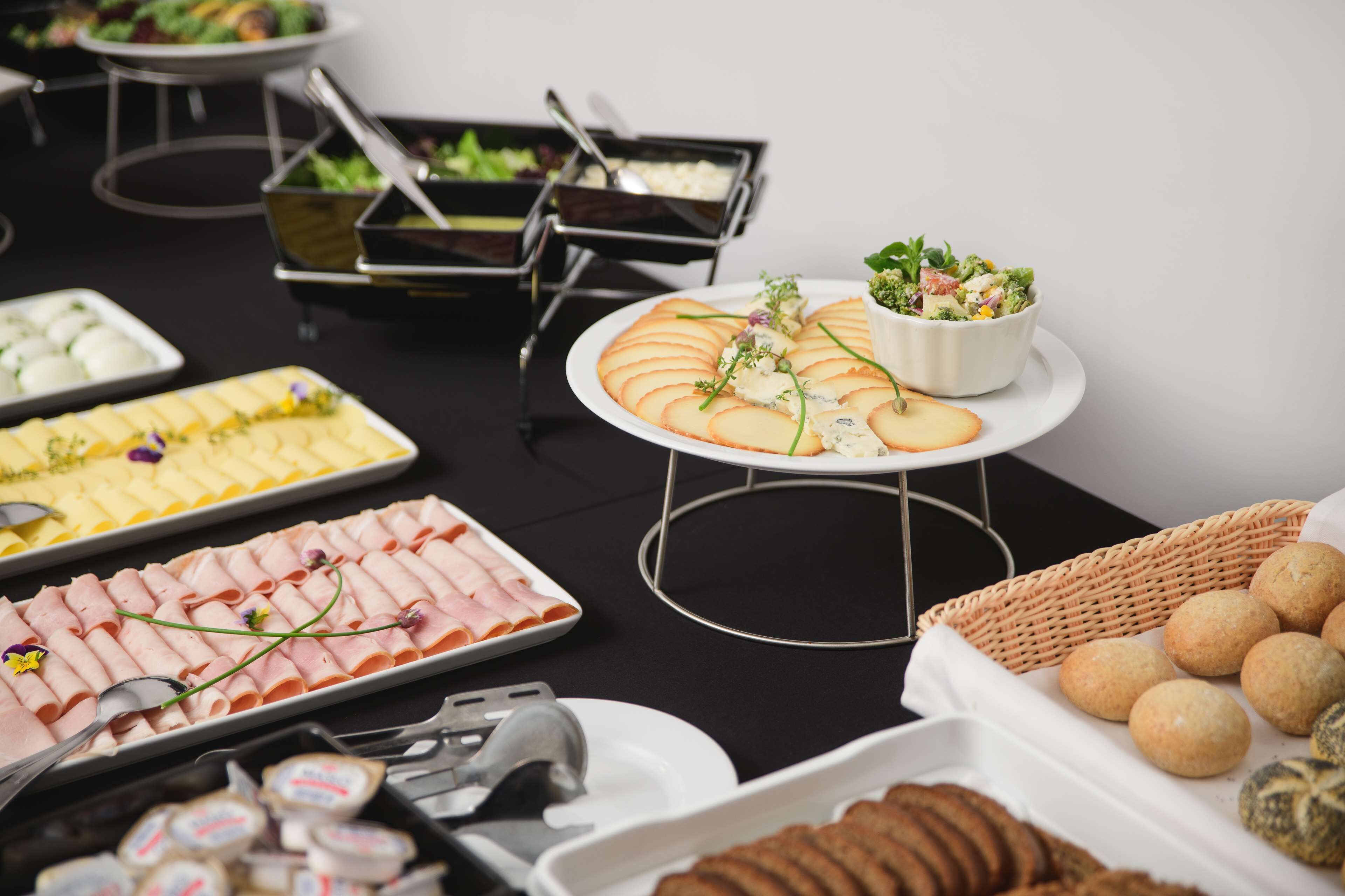 A buffet table with various food items including sliced meats, cheeses, and a salad.