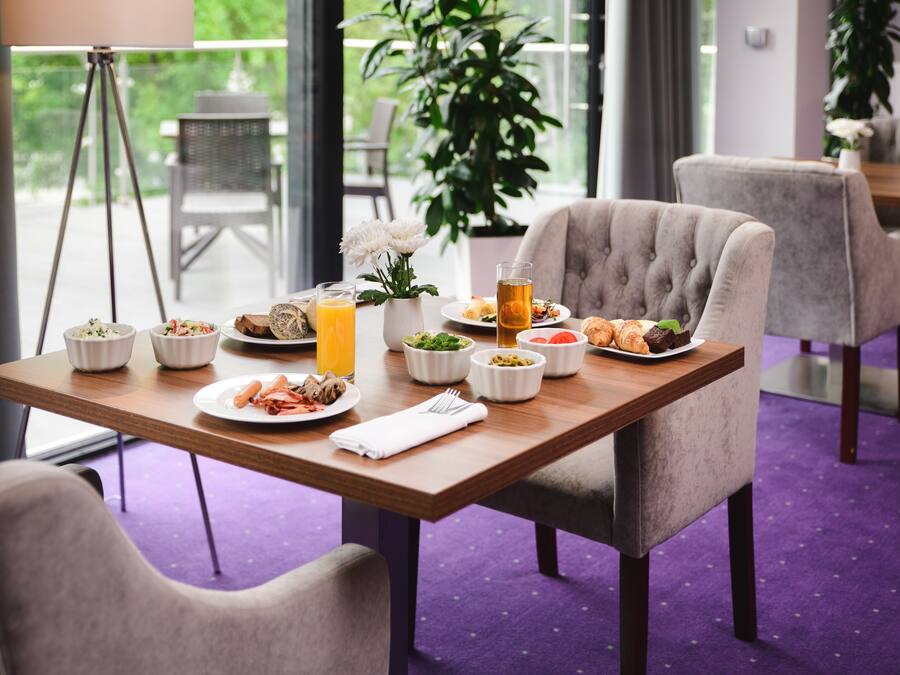 A dining table with various dishes, a glass of orange juice, and a tripod in the background.