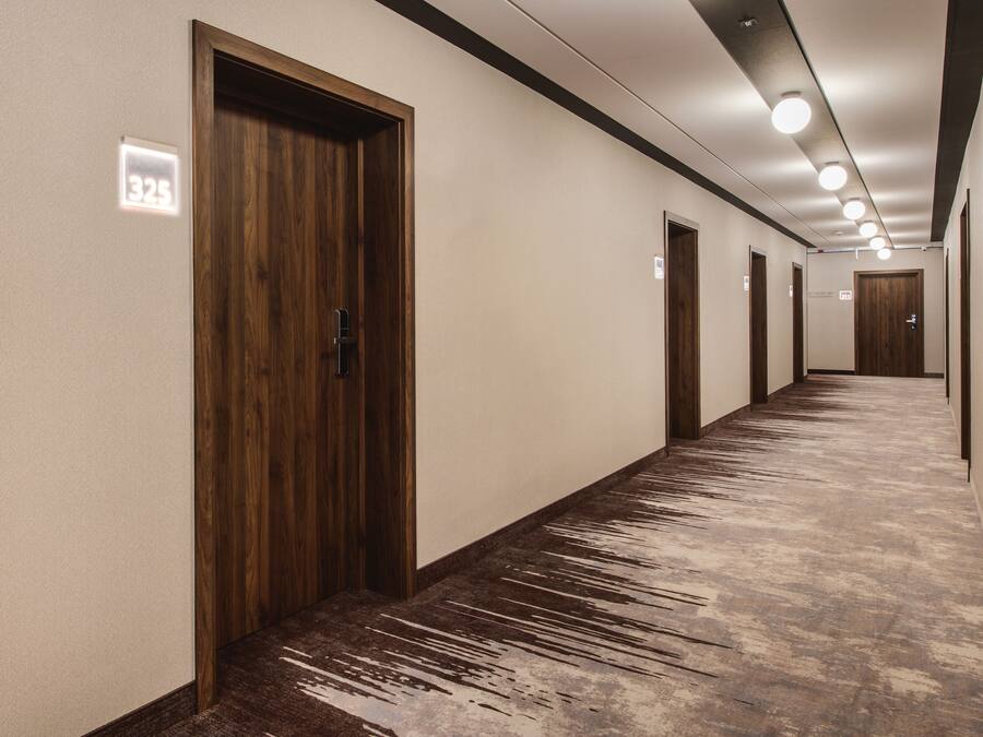 A long, narrow hallway with wooden doors and a textured carpet.