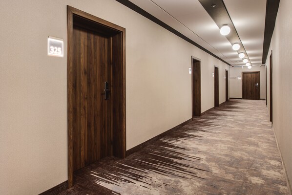 Un largo pasillo estrecho con puertas de madera y alfombra con textura.