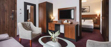 Habitación de hotel con cama, escritorio, televisor de pantalla plana, silla y mesa de centro.