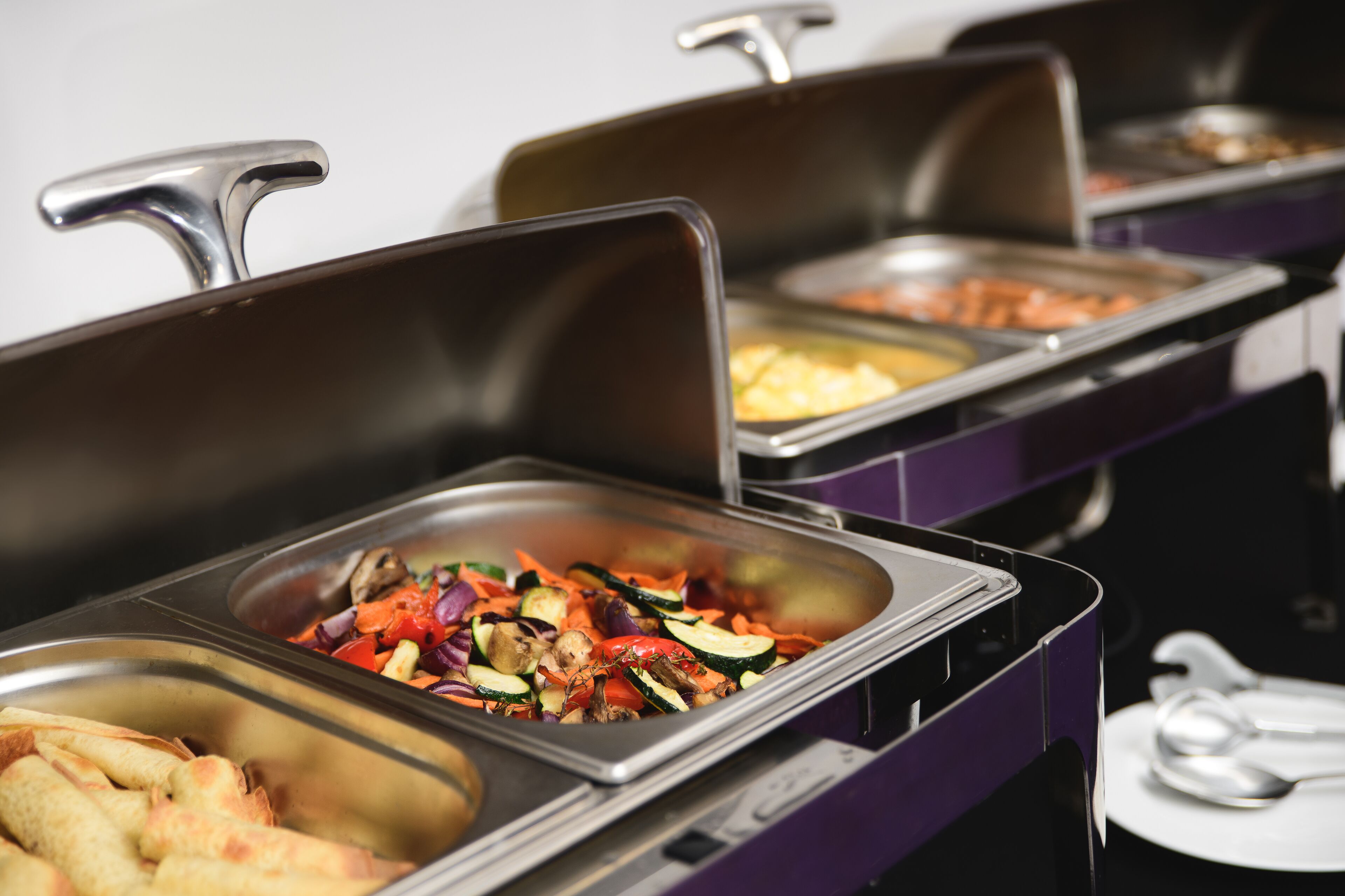 A buffet with various food options including vegetables and bread.