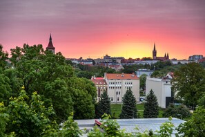 A cityscape with a prominent church spire and a modern building with a red roof.