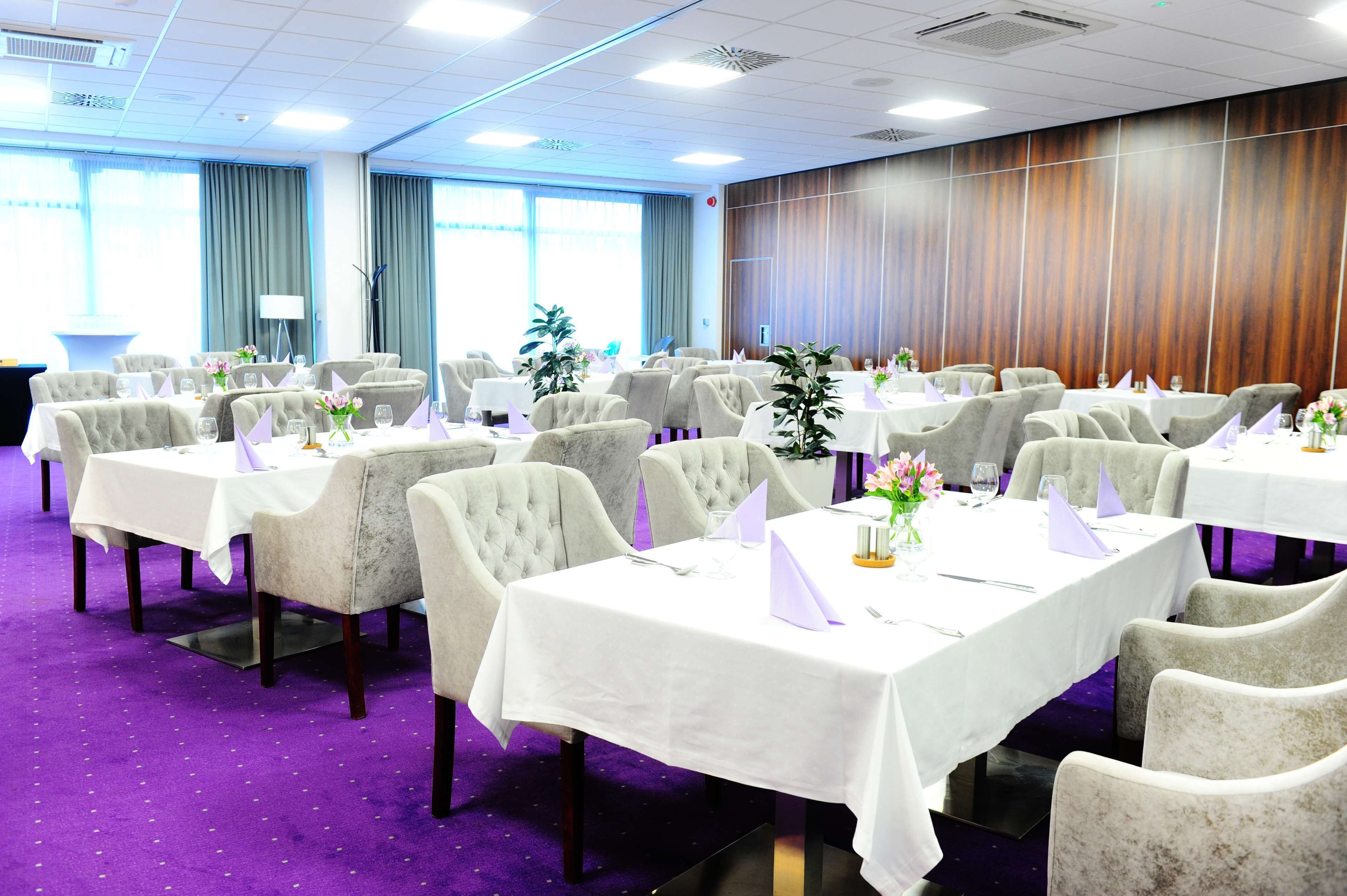 Un salón de conferencias con varias mesas y sillas dispuestas para una reunión o evento.