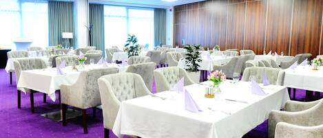 A conference room with multiple tables and chairs, arranged for a meeting or event.