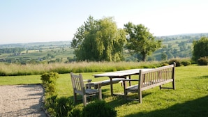 Un banc et une table sont installés sur une colline herbeuse, d’où l’on peut admirer un paysage magnifique.