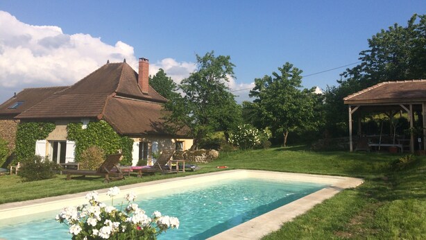 Un jardin avec une piscine, une maison et un kiosque.