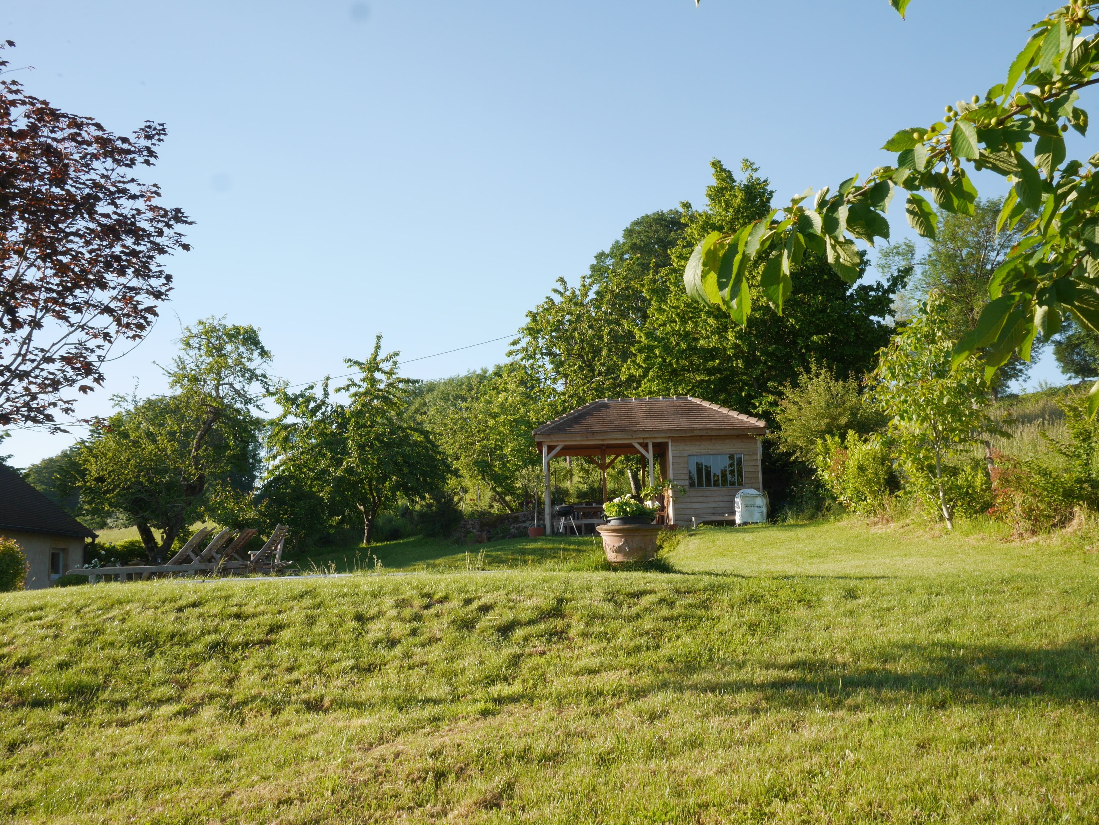 A house with a covered porch, a lawn, and surrounding trees.