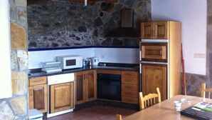 A kitchen with wooden cabinets, a microwave, and a stove. - Pitos House, Fijuecas (Fijuecas)