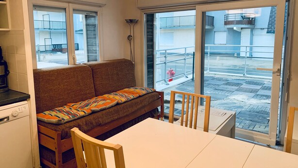 Une pièce confortable avec un canapé, une table à manger et des chaises. Il y a une fenêtre donnant sur l’extérieur.