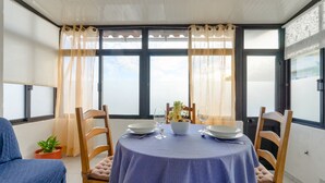 Een eetruimte met een ronde tafel gedekt voor twee personen, met een blauwe tafelkleed, twee stoelen, een kleine potplant en een decoratief middelpunt.