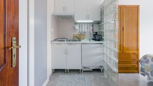 Een kleine keuken met witte kastjes, een koffiezetapparaat en een magnetron.