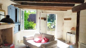 A cozy room with a sofa, a table, and a window overlooking greenery.