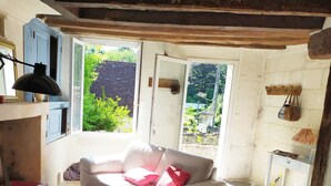 A cozy living room with a sofa, a wooden table, and a window with a view of greenery.