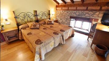 Un dormitorio con una cama grande, cabecera de madera, pared de piedra y un televisor sobre un mueble de madera.