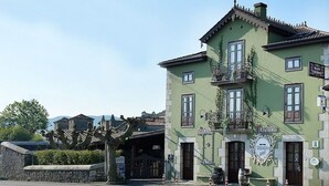 A two-story building with a green facade, multiple windows, and a balcony. - Posada Término (Entrambasaguas)