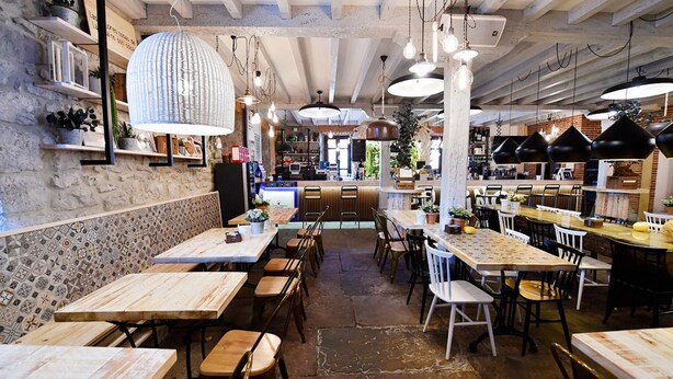 A restaurant interior with exposed brick walls, wooden tables, and hanging pendant lights. - Posada Término (Entrambasaguas)