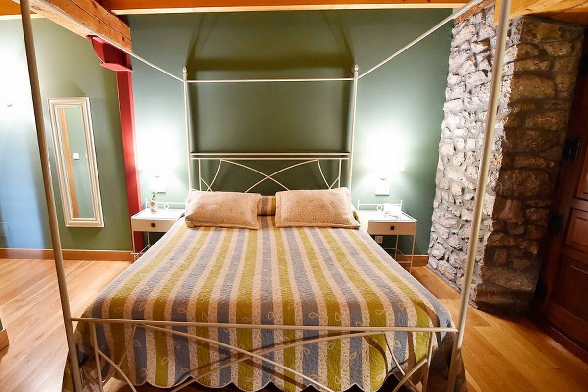A bedroom with a bed, bedside tables, and a stone wall.