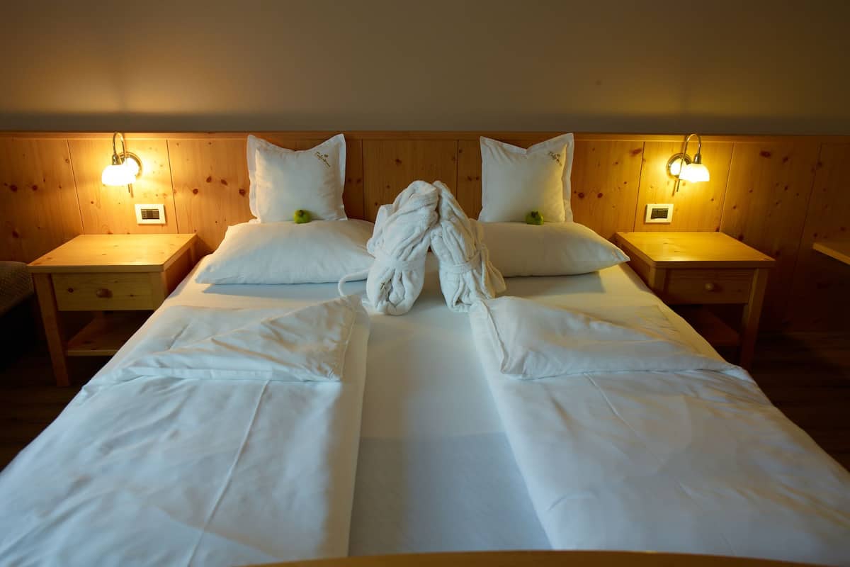 A neatly made bed with white linens, two bedside tables with lamps, and a wooden headboard.