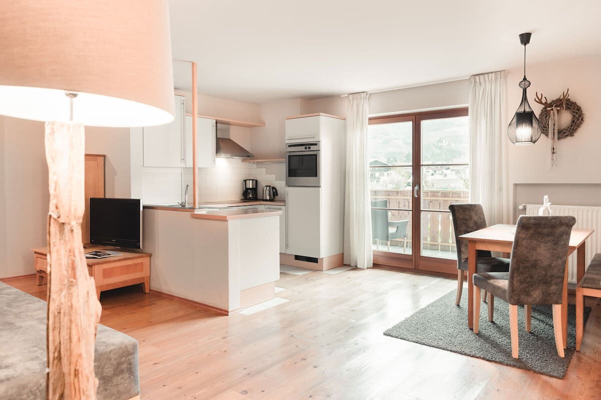 A modern apartment with a kitchen, dining area, and a balcony with a view.