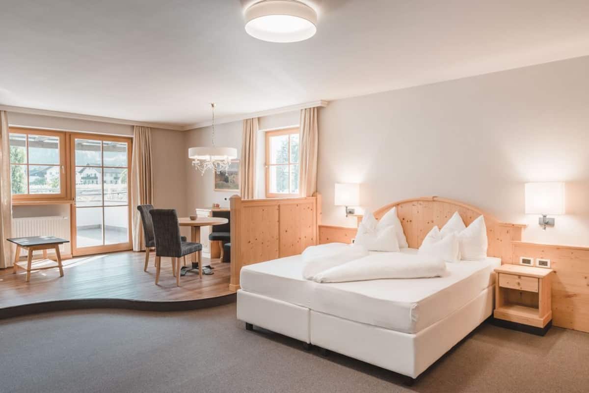 A hotel room with a bed, a desk, a chair, and a view of the outside.