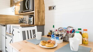A kitchen with wooden cabinets, a microwave, and a coffee maker. There are breakfast items on the counter, including eggs, a muffin, and a bottle of orange juice. - Weedingshall Lodges (Falkirk)