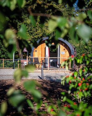 Une cabane en bois avec un toit incurvé, une terrasse entourée d’une clôture et un panneau indiquant son numéro.