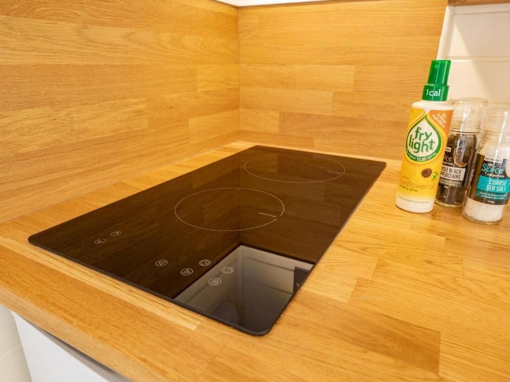 Una cocina con placa de inducción negra y muebles de madera.