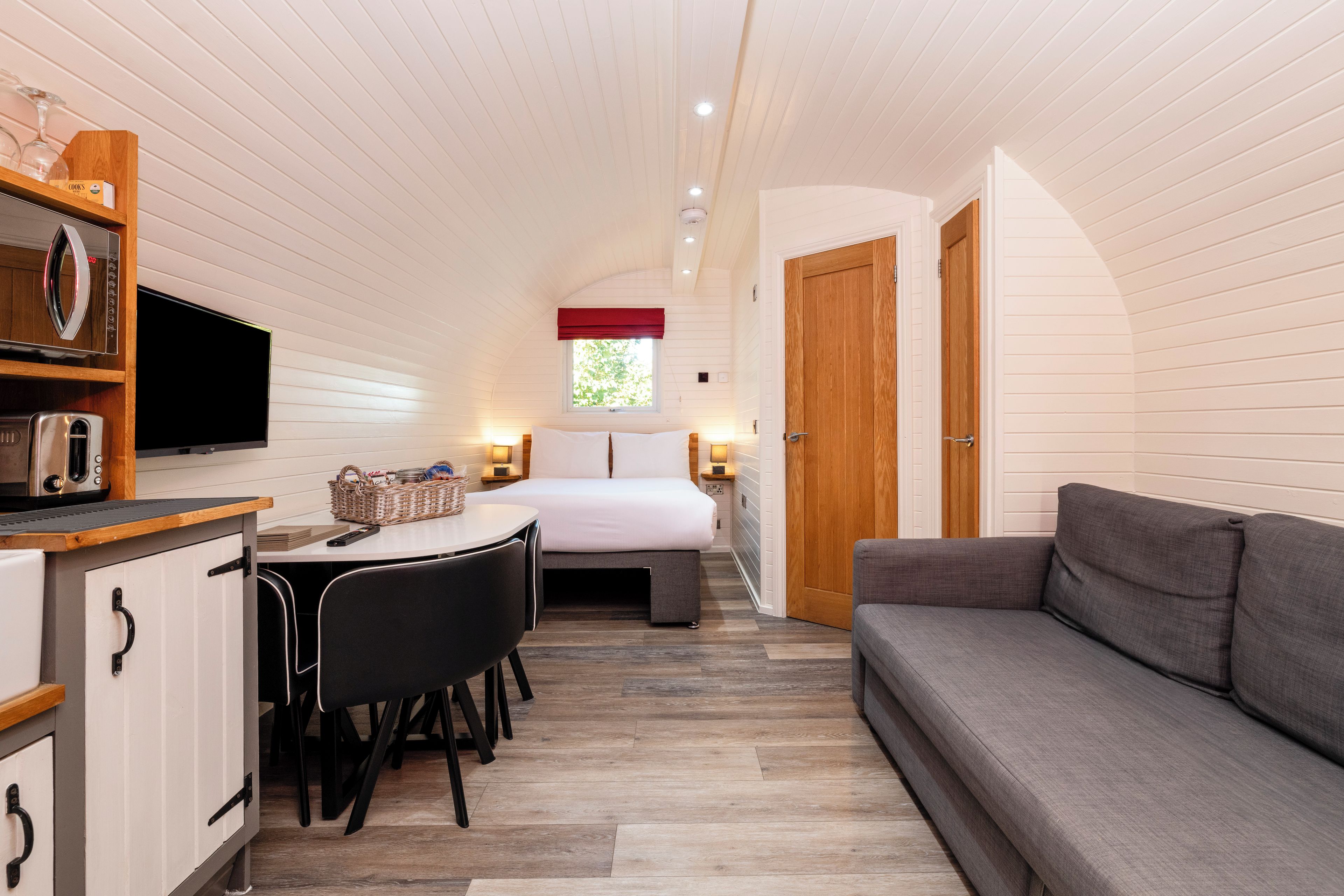 A compact room with a kitchenette, a dining area, a bed, and a sofa.