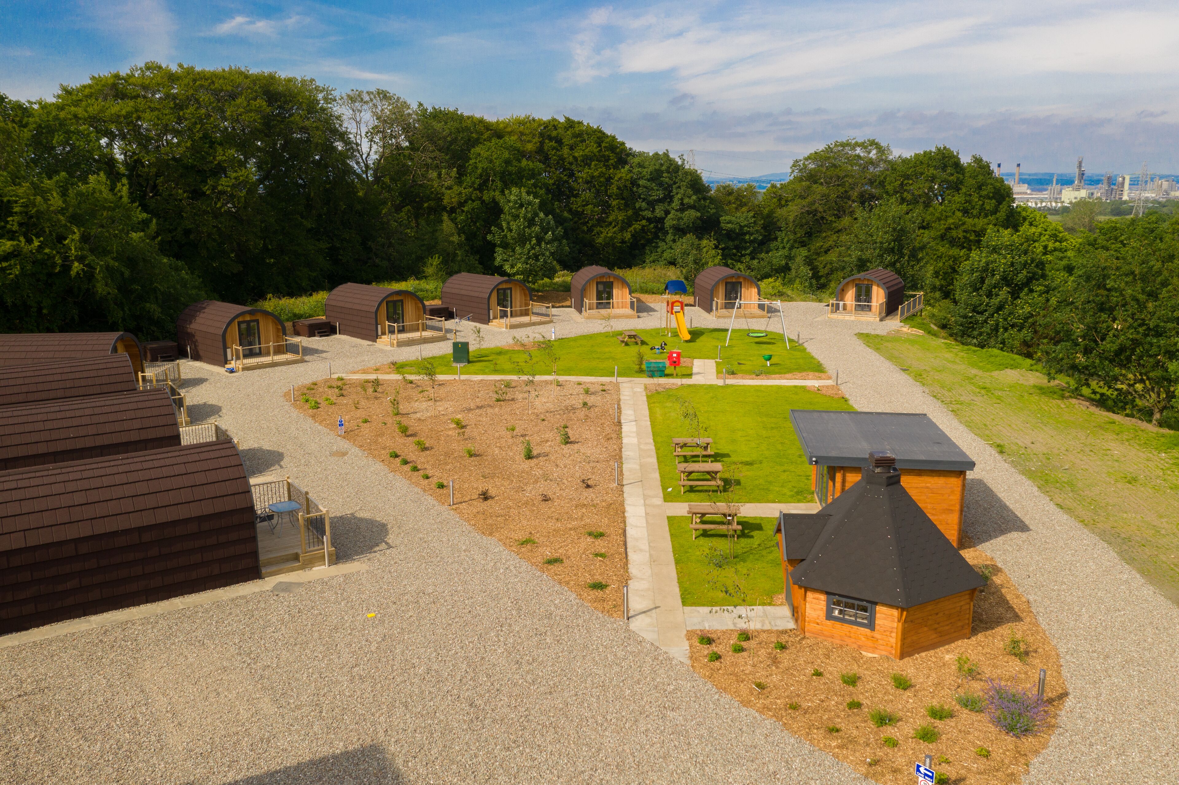 Un camping con varias cabañas de madera, un parque infantil y una zona de picnic.