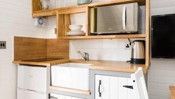 A compact kitchen with a built-in oven, a sink, and a microwave.